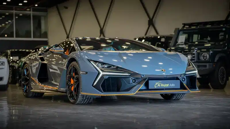 Elegant blue sports car displayed in a luxurious indoor car showroom setting.