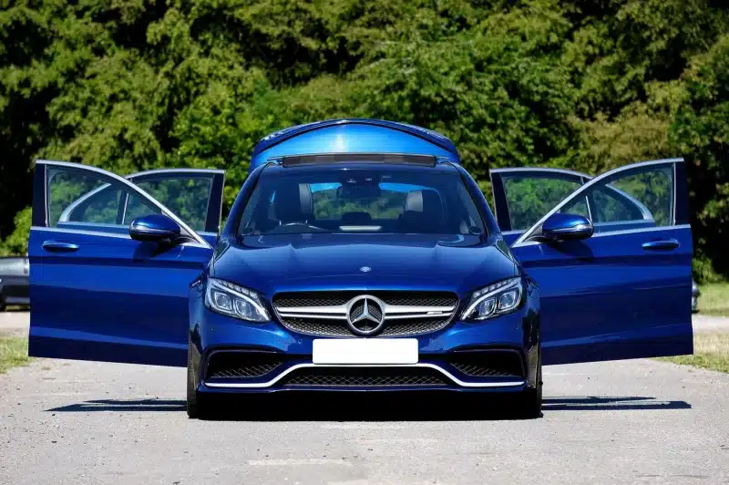 Elegant blue sports car with open doors on a sunlit rural road. Perfect for automotive enthusiasts.
