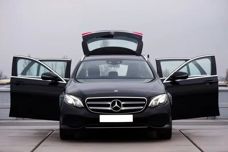 Front view of a luxury black Mercedes-Benz car with all doors and trunk open, showcasing elegance and style.