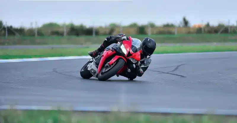 Motorcycle racer leaning into a turn on the racing track, showcasing speed and precision.