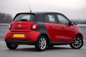 Rear view of a red Smart Forfour parked outdoors on a cloudy day, showcasing sleek design.
