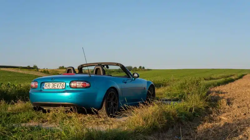 A blue convertible in the scenic countryside of Słomniki, Poland on a sunny day.