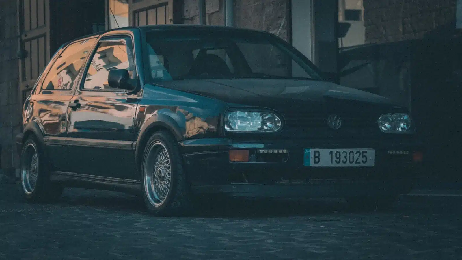 A classic Volkswagen Golf hatchback parked outdoors in Lebanese urban setting.