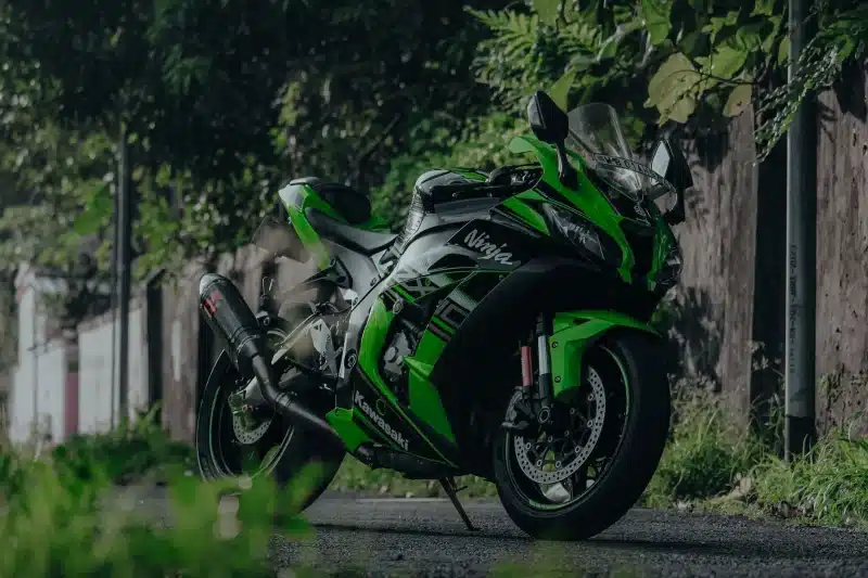 A sleek Kawasaki Ninja ZX-10R motorcycle parked on a lush roadside in India.