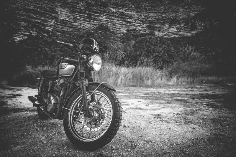 Classic Triumph motorcycle parked outdoors in a black and white setting, exuding vintage charm.