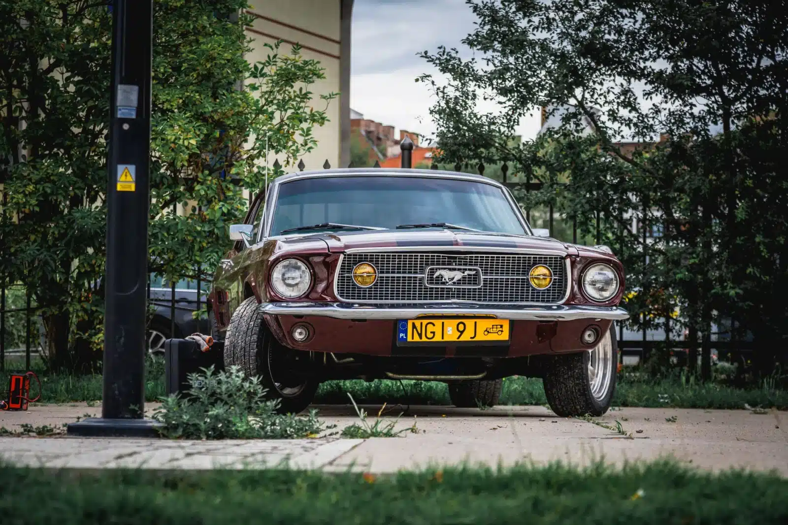 Front view of a vintage red Ford Mustang parked outdoors, showcasing its classic design