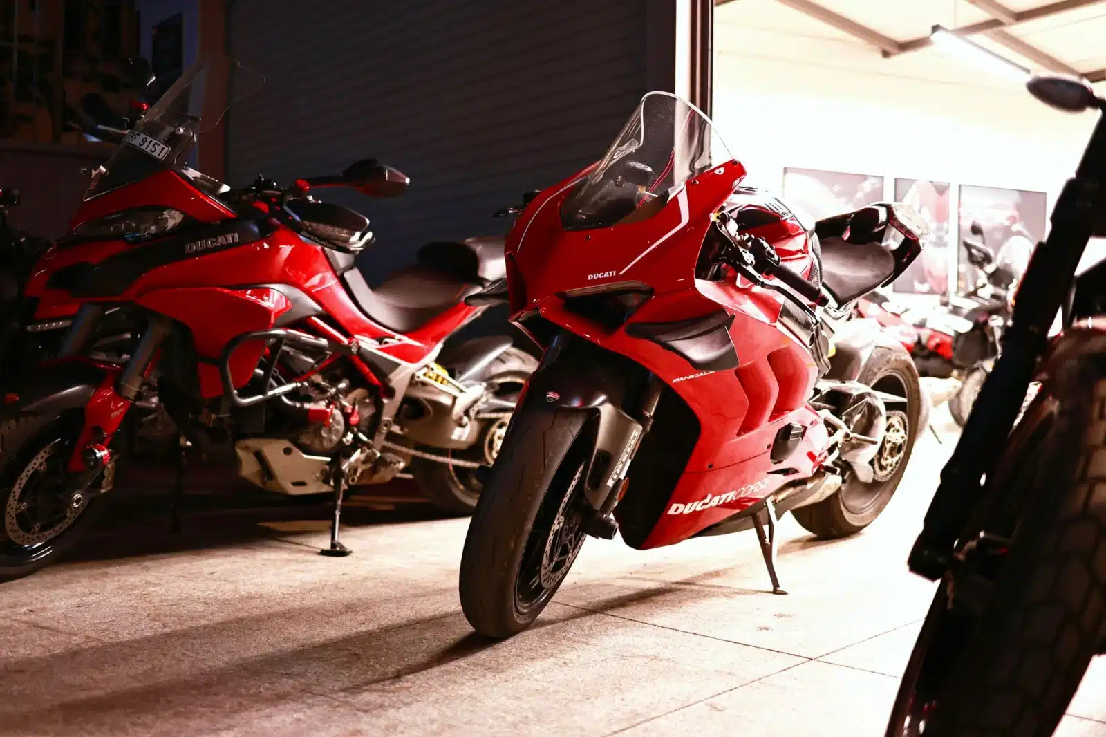 Sleek red Ducati motorcycles parked inside a Bengaluru garage at night, showcasing modern design and engineering.